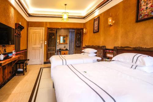 a bedroom with two beds and a desk and a television at Huaqianshu Theme Inn in Wang-ts'un