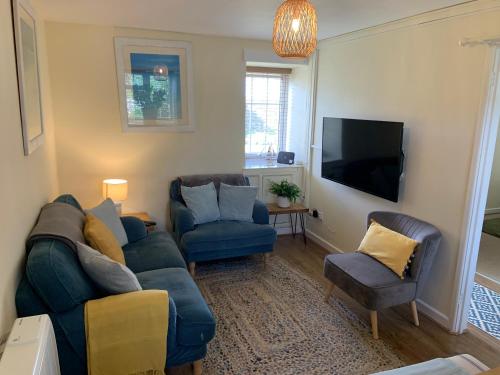 a living room with a blue couch and two chairs at Large 3 bedroom flat in Sennen in Penzance