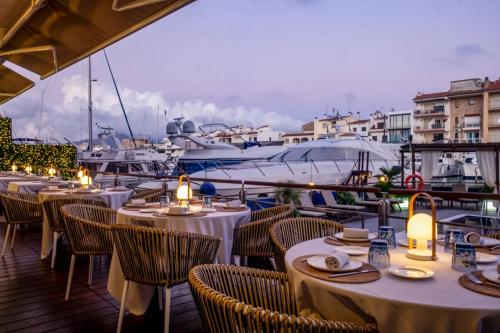 a restaurant with tables and chairs on a dock with boats at Hotel Port Salins by Pierre & Vacances in Empuriabrava