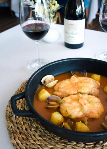 a bowl of chicken and vegetables with a glass of wine at Hotel Port Salins by Pierre & Vacances in Empuriabrava