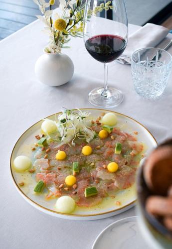 a plate of food on a table with a glass of wine at Hotel Port Salins by Pierre & Vacances in Empuriabrava