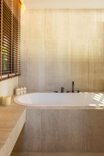 a large bath tub in a bathroom with a window at Legend Hill Resort and Spa in Rivière Noire