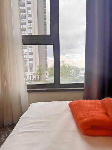 a bed with an orange pillow in front of a window at BW Verde Icon in Belgrade