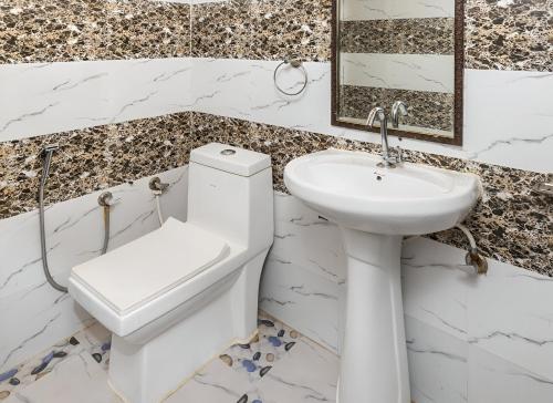 a white bathroom with a toilet and a sink at Mid Forest House - Jim Corbett in Rāmnagar