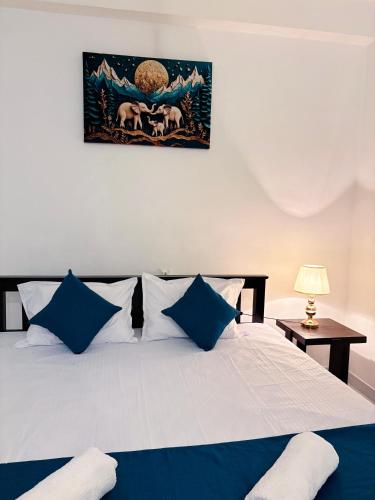 a bedroom with a large bed with blue pillows at Muthumala Villa in Tangalle