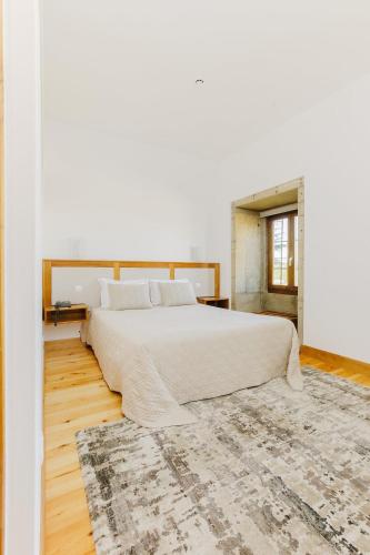 a bedroom with a large bed and a rug at Hotel Rural Casa de Samaioes in Chaves