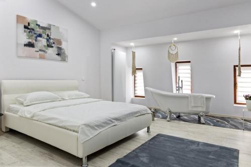 a white bedroom with a bed and a chair at Selari Boutique in Bucharest