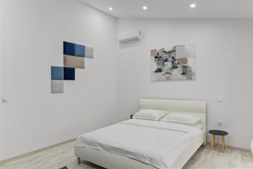 a white bedroom with a bed and paintings on the wall at Selari Boutique in Bucharest