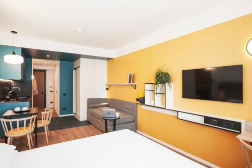a living room with a yellow wall with a flat screen tv at Aparthotel Colombo Roma in Rome