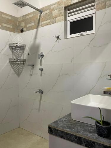 une salle de bain blanche avec un lavabo et un miroir dans l'établissement Mount Lavender Weligama, à Weligama