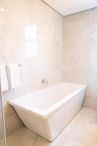 a white bath tub in a bathroom with white tiles at Zar Hotel in Amanzimtoti