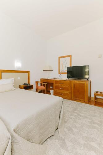 a bedroom with a bed and a flat screen tv at Hotel Rural Casa de Samaioes in Chaves