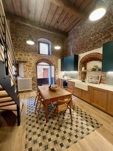 a kitchen with a wooden table and a brick wall at Casa Betta - A 700 Year Old Tuscan Gem in Chiusdino