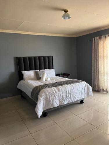 a bedroom with a large bed with a black headboard at The Comfort Cottage in Saulspoort