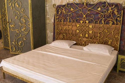 a large bed with a gold headboard and white pillows at Casa Paradise in Dilijan