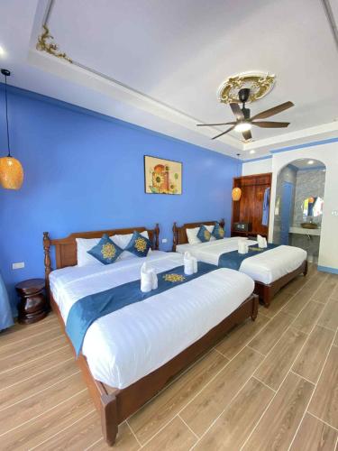 a bedroom with two beds and a blue wall at Sadakham Royal View Hotel in Luang Prabang