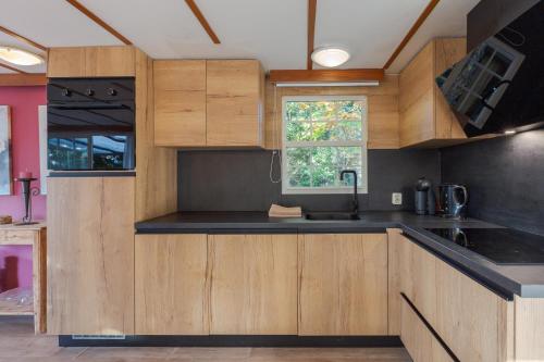 a kitchen with wooden cabinets and a window at chalet in Putten