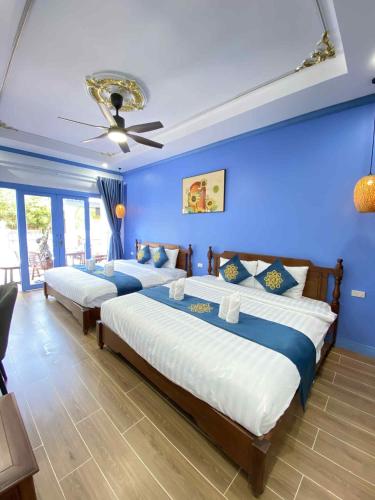 two beds in a room with blue walls at Sadakham Royal View Hotel in Luang Prabang