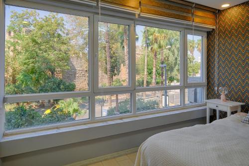 ein Schlafzimmer mit großen Fenstern mit Blick auf einen Garten in der Unterkunft Maxihomes Near Hadrian Gate & Beach, with Sea Views in Antalya
