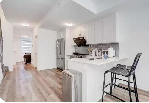 a kitchen with white cabinets and a black chair in it at Downsview Park Townhome queen bed near Yorkdale Transit in Toronto