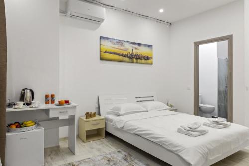 a white bedroom with a bed and a desk at Selari Boutique in Bucharest