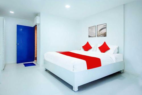 a white bedroom with a white bed with red pillows at To The Sea by Belvilla in Na Jomtien