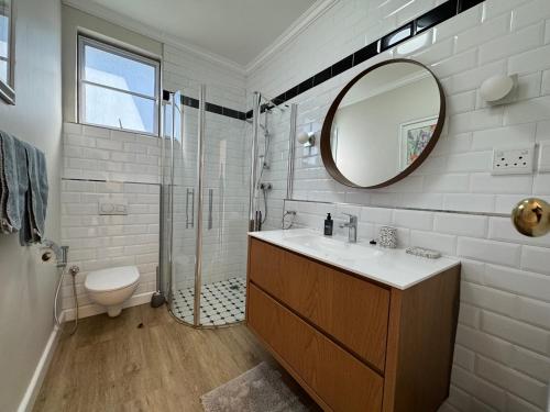 a bathroom with a sink and a shower with a mirror at The Tableview Garden Room in Cape Town