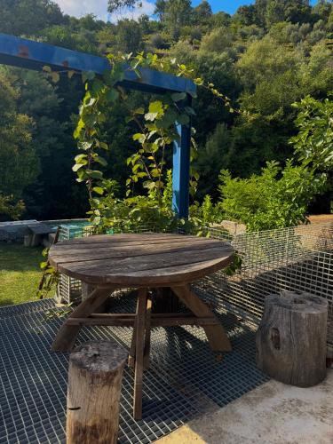 a wooden picnic table with two logs around it at Quinta São José - Museu do Triciclo in Mesão Frio
