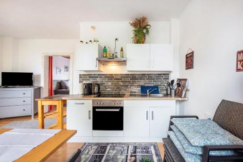 a kitchen and living room with white cabinets and a couch at Tiny Home in Lübeck