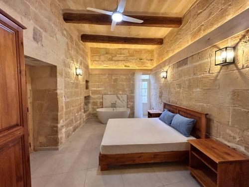 a bedroom with a large bed and a bath tub at Ta' Marija in Sannat