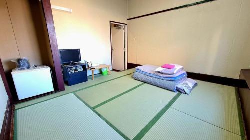 a room with a room with a bed and a tv at ビジネス旅館 錦荘 - Nishiki Guest House in Kadoma