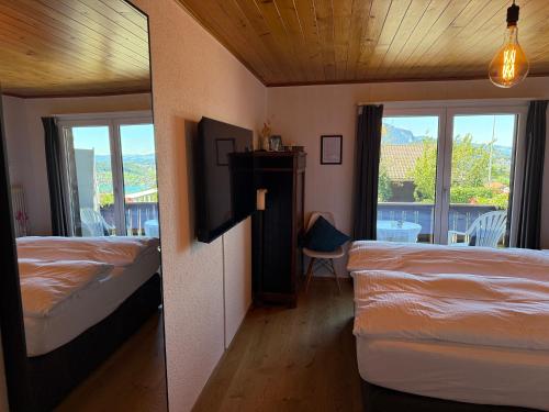 a hotel room with two beds and a balcony at Eva's Seeblick in Krattigen