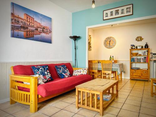ein Wohnzimmer mit einem roten Sofa und einem Tisch in der Unterkunft La Petite Maison in Marseillan