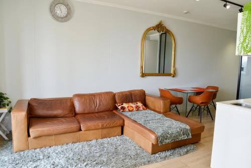 sala de estar con sofá de cuero marrón y espejo en Luxury Escape at Ellipse 1-Bed, Kitchen, Wi-Fi & Free Parking, en Midrand