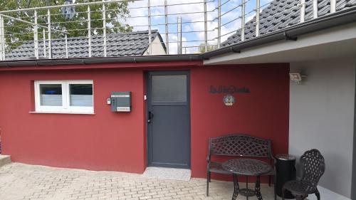 Un edificio rojo con una puerta, una mesa y sillas. en La Hasienda, en Geldern