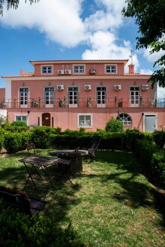 un grand bâtiment rose avec une table devant dans l'établissement WOT Sintra Sarrazola, à Sintra