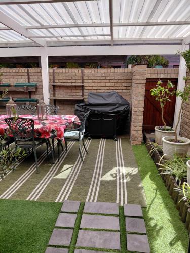 un patio con una mesa y una pérgola blanca en Blouberg Beach Villa, en Ciudad del Cabo