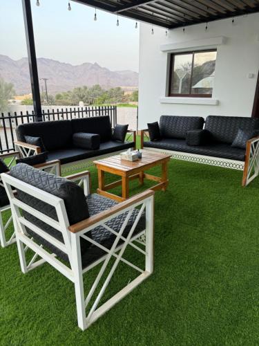 a patio with green grass and a table and chairs at Alhara Lodge استراحة الحارة in Hatta