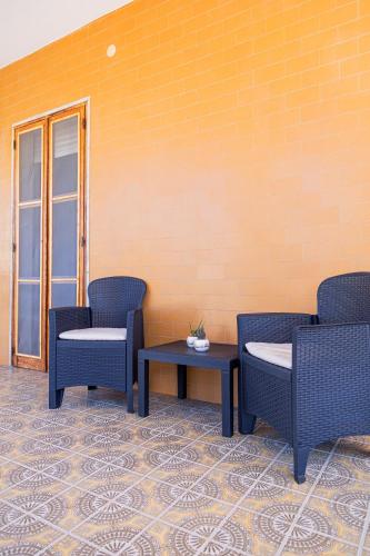 three chairs and a table in front of a wall at Al numero 1 in Nova Siri Marina