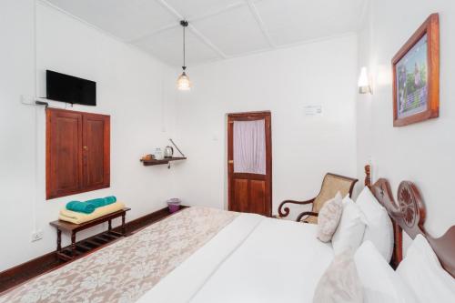 a white bedroom with a bed and a tv at The Golf Green City Bungalow in Nuwara Eliya
