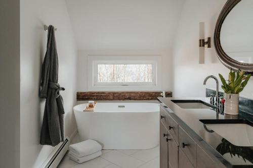 a bathroom with a large white tub and a sink at Luxe Gabel Farmhouse Fire Pit & Country Views in Callicoon