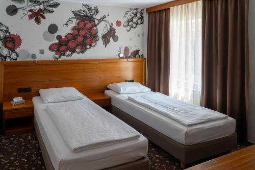 a hotel room with two beds and a window at Hotel Piramida in Maribor