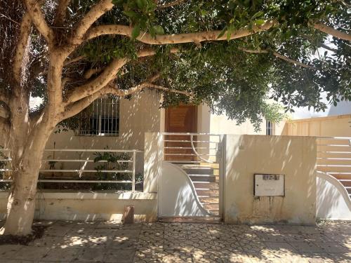 a tree sitting next to a white wall next to a tree at Family villa in Saïdia in Saidia 