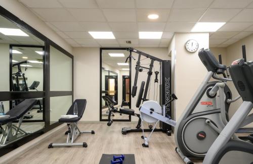 a gym with tread machines and a clock at Leonardo Hotel Budapest in Budapest