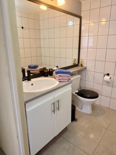 a bathroom with a sink and a toilet and a mirror at Bon Bini na Curacao in Willemstad