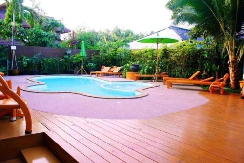 a pool on a wooden deck with chairs and an umbrella at Dancenter Bupatara Chiangmai in Chiang Mai