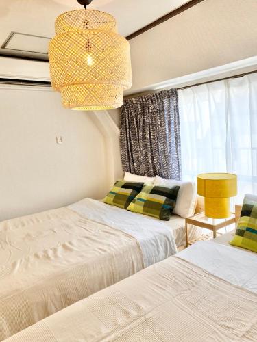 a bedroom with two beds and a chandelier at 恵比寿駅から徒歩1分 渋谷3分 新宿10分 30m2でゆったり 最高の立地 403号室 in Tokyo