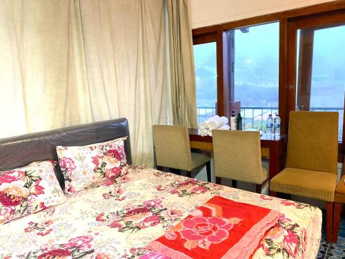 a bedroom with a bed and a table and windows at PRO Batu Embun Pagi Hotel in Punten