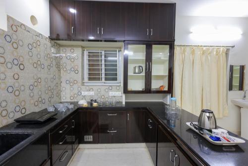 a kitchen with brown cabinets and a counter top at SBHS Venkatadri Homestay in Tirupati