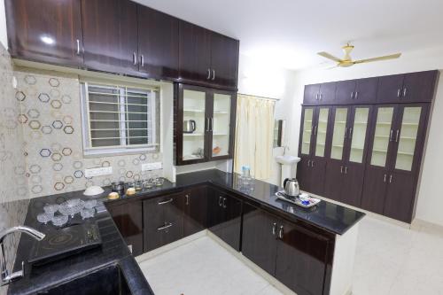 a kitchen with dark wood cabinets and a sink at SBHS Venkatadri Homestay in Tirupati